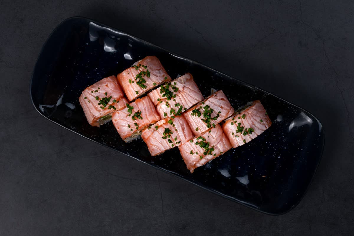 Holbæk Roll: otte stykker uramaki toppet med flamberet laks på et sort fad.